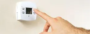 Hand adjusting a home thermostat