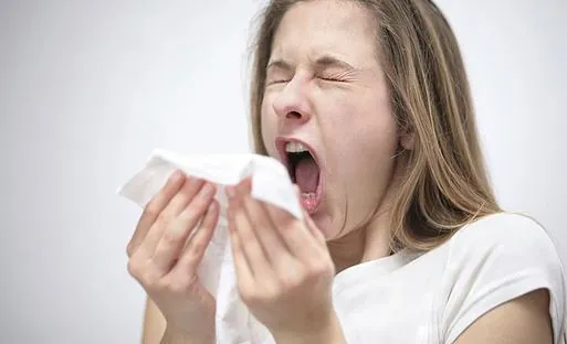 Woman sneezing from dust and allergies